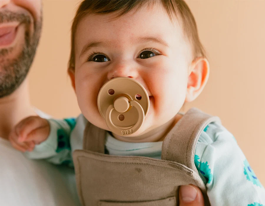 Image of a smiling baby with a BIBS USA natural pacifier