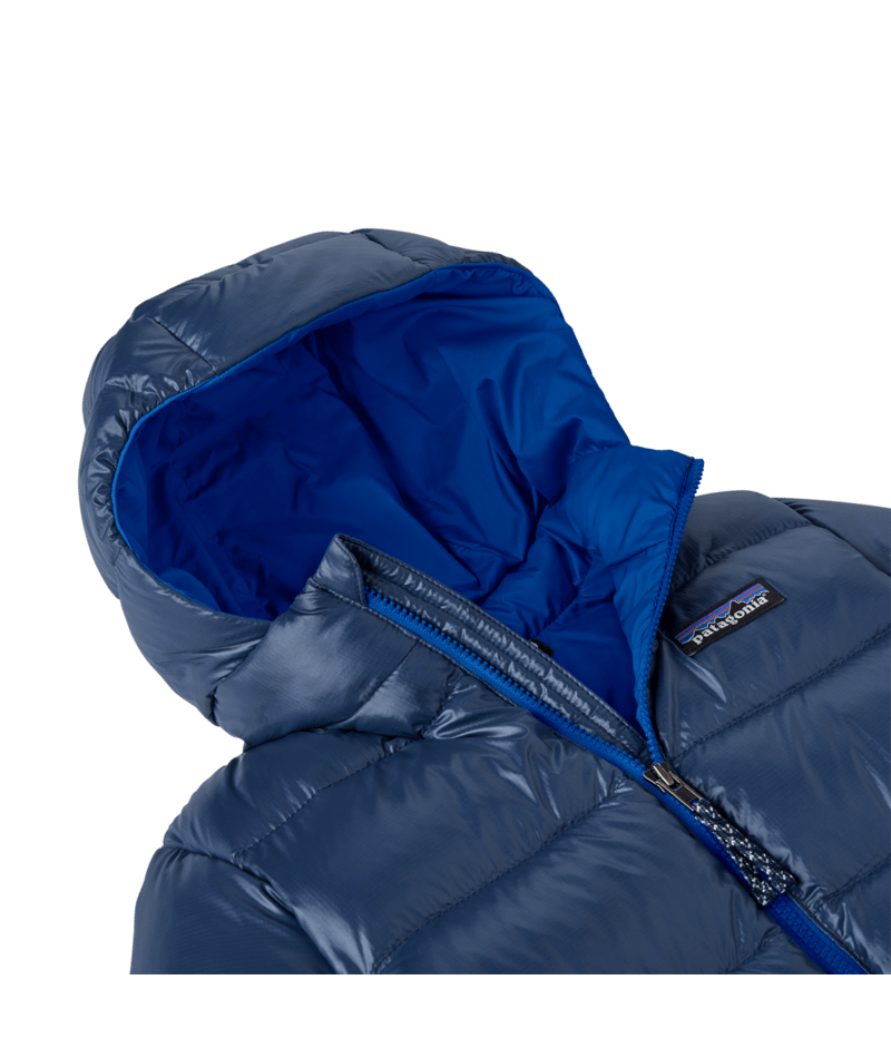 Close-up of a puffer jacket showing the hood, shiny navy blue exterior, bright royal blue inner hood lining, and a visible Patagonia logo patch on the chest.