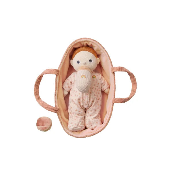 Baby doll in a pink crib on a white background