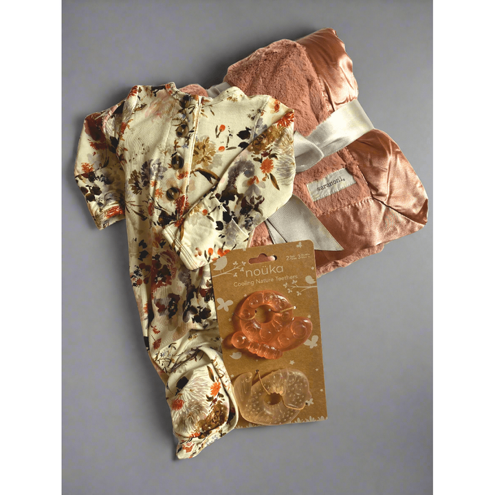 Baby outfit with floral pattern and pink blanket, featuring a tag on a white background