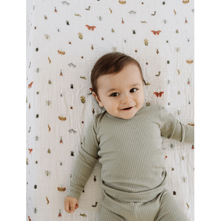Baby lying on a patterned blanket wearing a green outfit