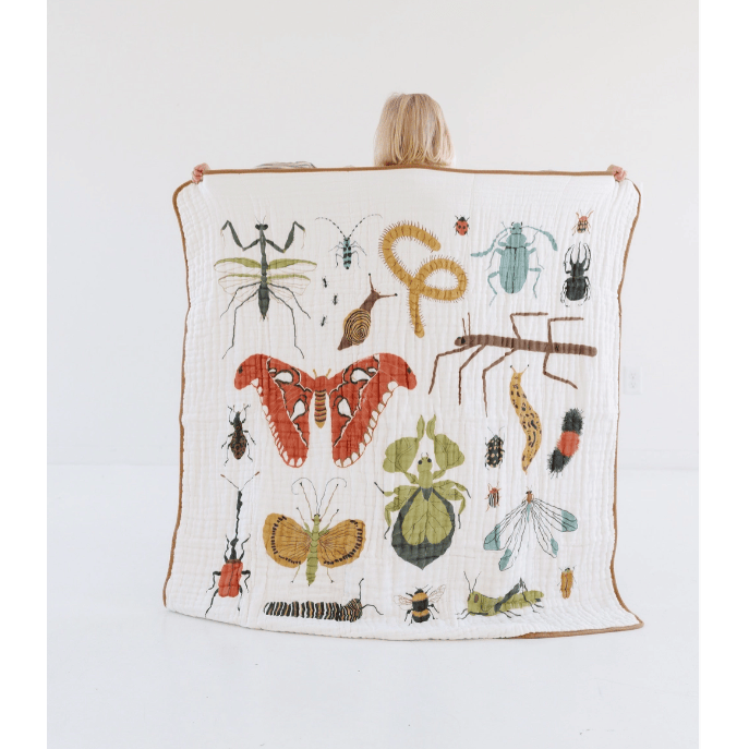 Person holding a quilt with insect illustrations on a white background
