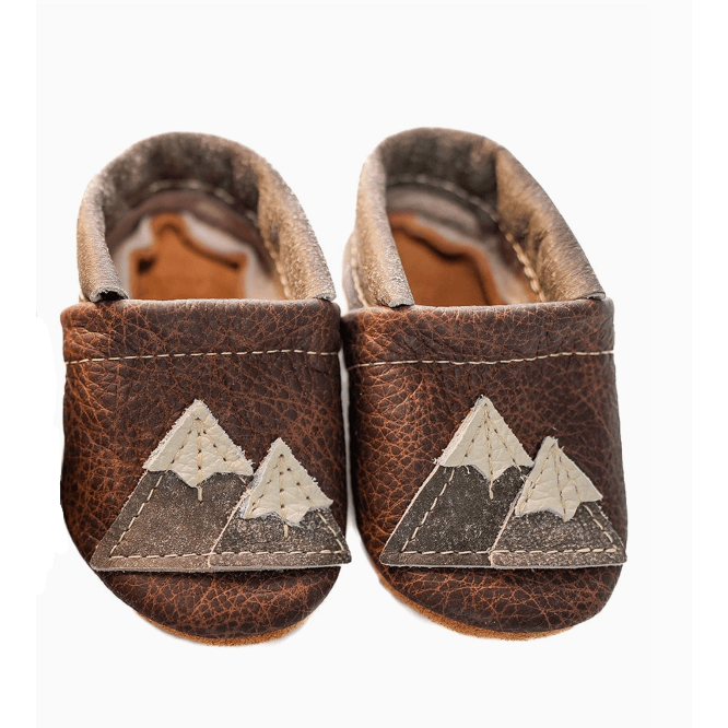 Pair of brown leather baby shoes with mountain design on a white background