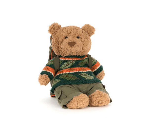 Teddy bear wearing a striped sweater and backpack on a white background