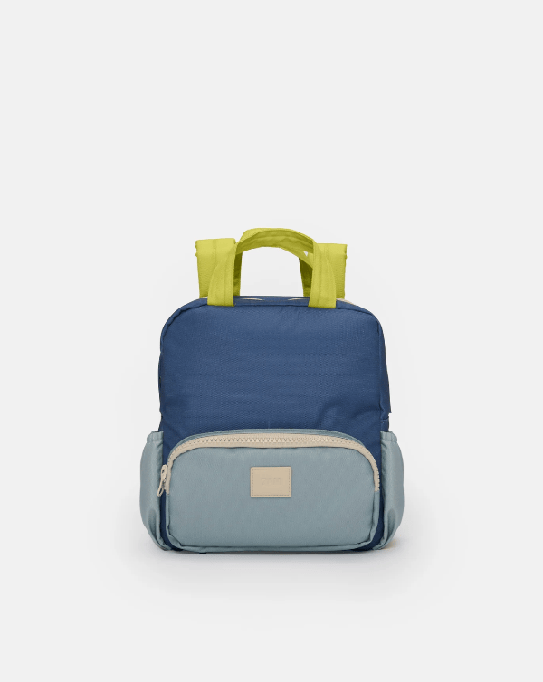 A color-blocked nylon backpack in navy blue, light blue, and lime green, featuring a top handle and a front zippered pocket with a beige brand patch.