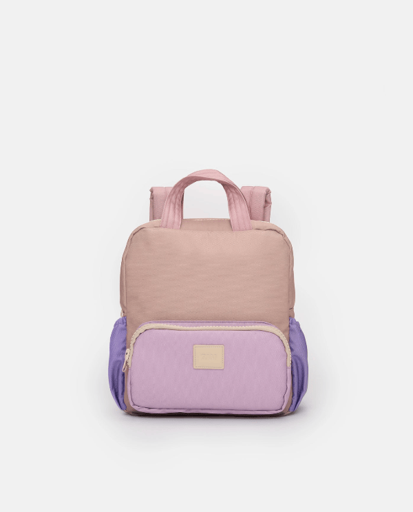 A color-blocked nylon backpack in shades of dusty pink, lavender purple, and light blue, featuring a top handle and a front zippered pocket with a small beige brand patch.