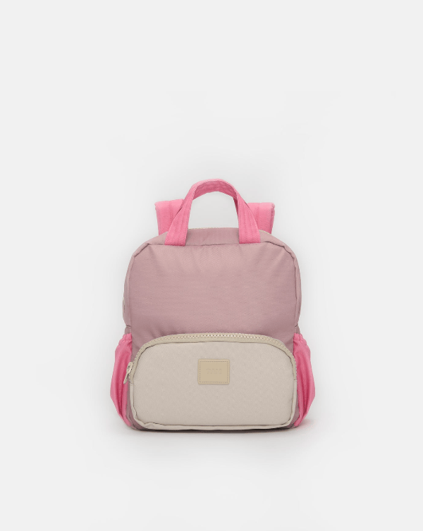A small backpack in dusty pink and cream, featuring a top handle, pink shoulder straps, and a cream-colored front zippered pocket with a small beige brand patch.