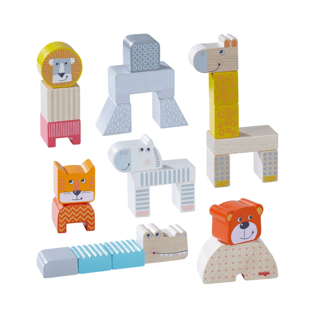 A set of wooden animal and geometric building blocks by Maja, arranged on a clean white background. The blocks feature various animal designs including a lion, giraffe, zebra, cat, crocodile, and bear, alongside simple geometric shapes in natural wood, light blue, yellow, and gray.