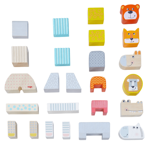 A set of colorful wooden toy blocks and animal-shaped pieces arranged on a plain white background. The pieces include striped, dotted, patterned, and solid wood designs, plus animal faces such as a bear, fox, lion, crocodile, and hippo.