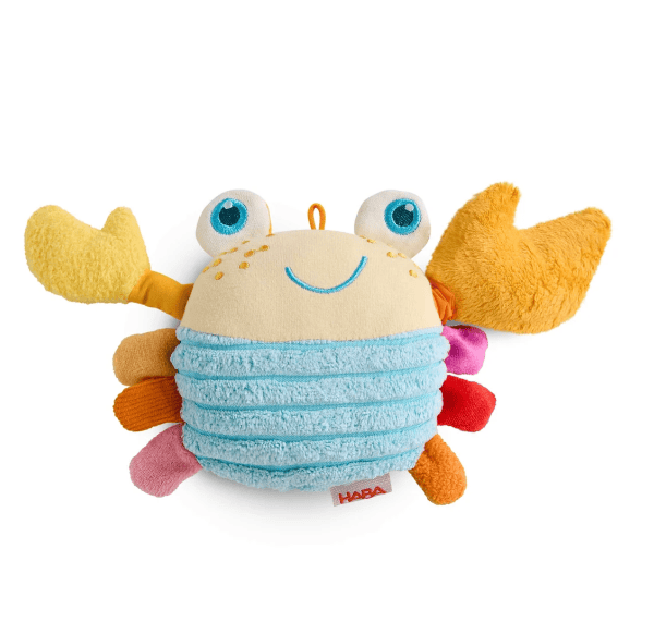 A HABA plush crab baby toy with a textured light blue striped body, cream-colored face, yellow claws, and multicolored legs, shown on a solid white background.