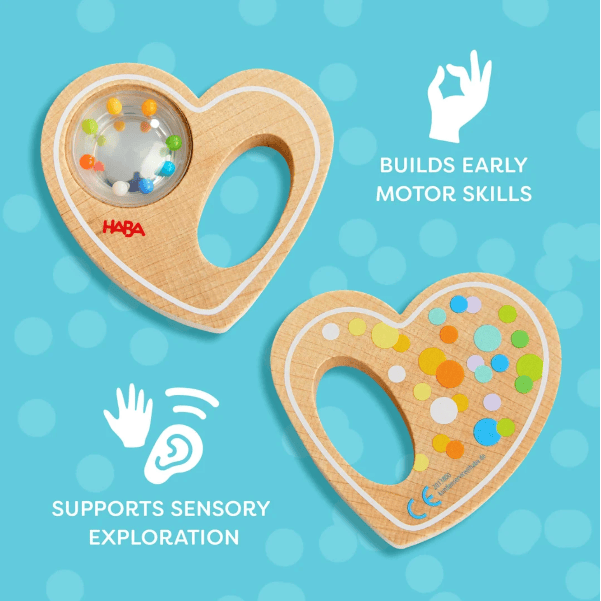 Two HABA wooden heart-shaped sensory toys on a light blue polka-dot background, with white text and icons describing developmental benefits: &