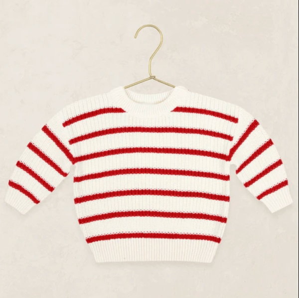 A white knit sweater with horizontal red stripes, hanging on a gold metal hanger against a light beige textured background.