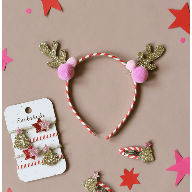 Christmas-themed headband with pom-poms and decorative clips on a brown background
