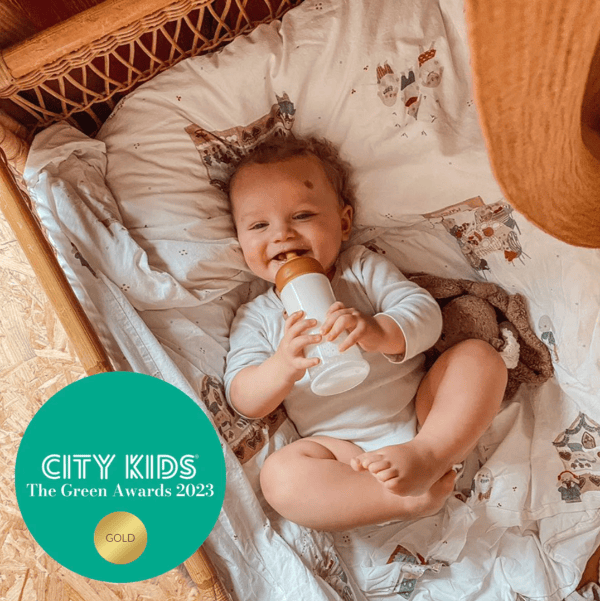 Baby lying in a crib holding a bottle, with 'City Kids' award logo at the bottom.