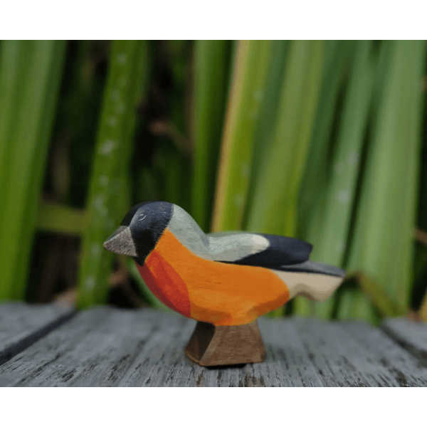 Wooden bird figurine on a wooden surface with a blurred green background