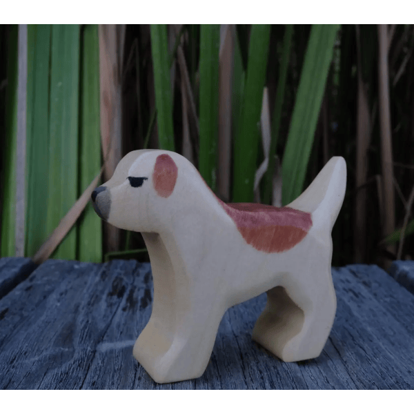 Wooden dog-shaped planter on a textured surface with a green plant in the background