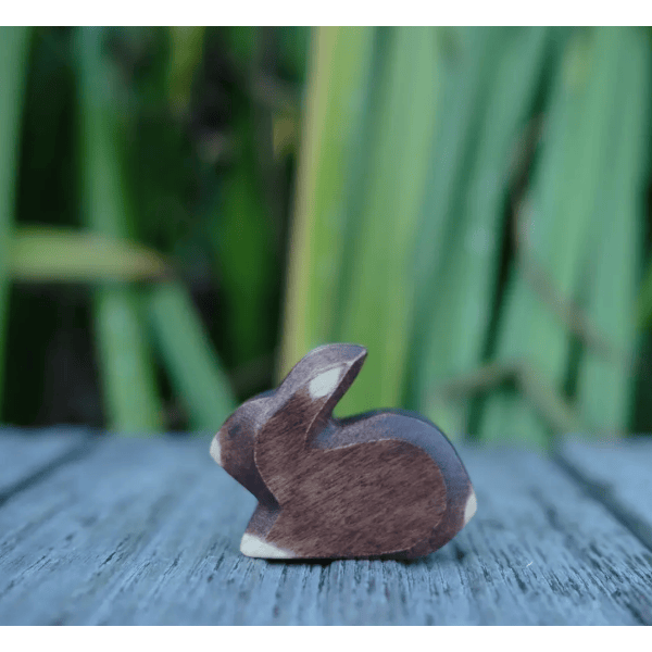 Wooden rabbit figurine on a wooden surface with a blurred green background