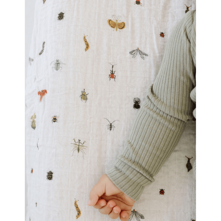 Close-up of a textured fabric with insect patterns and a person's sleeve.