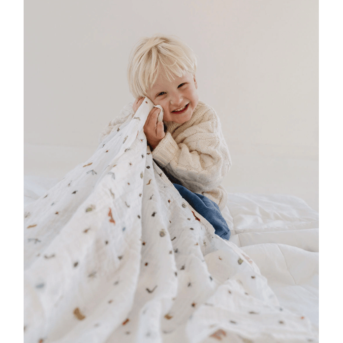 Child wrapped in a patterned blanket against a plain background