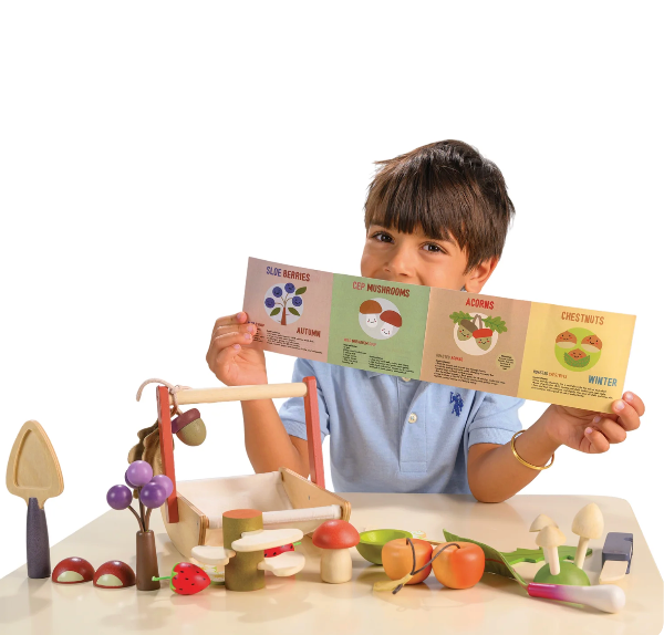 Child holding educational cards with a toy vegetable set on a white background
