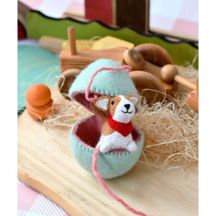 Small felted animal toy inside a felted ball with a wooden background