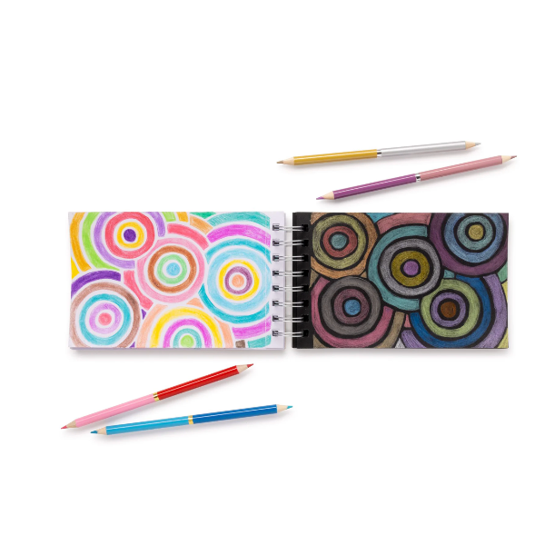 Colorful spiral-bound notebook with circular patterns and three colored pencils on a white background