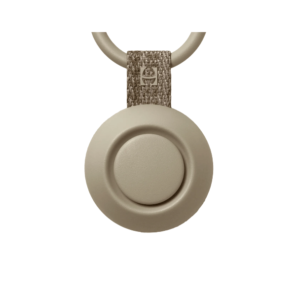 Round beige device with a textured keychain on a beige background