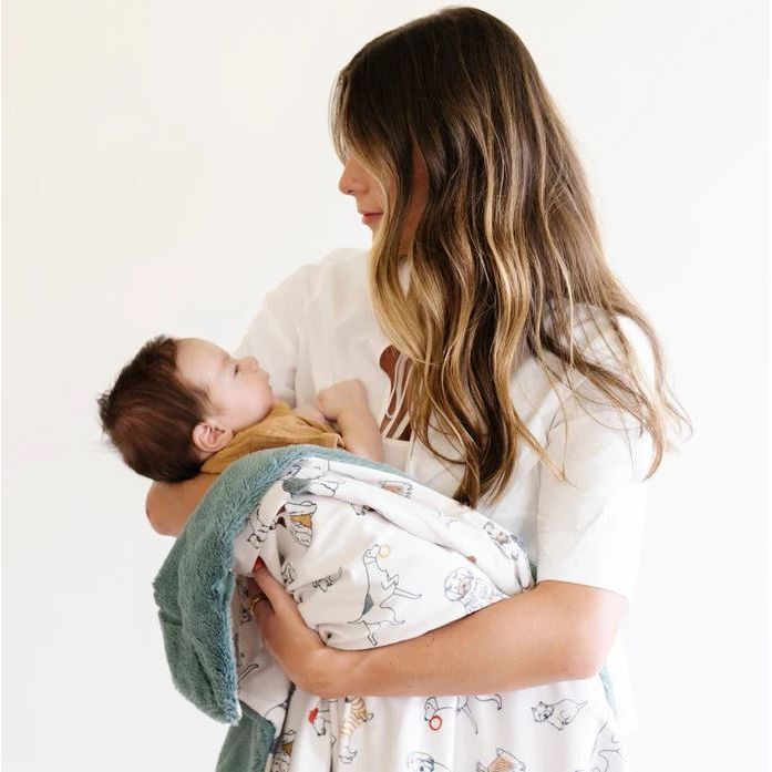 Woman holding a baby wrapped in a blanket against a white background
