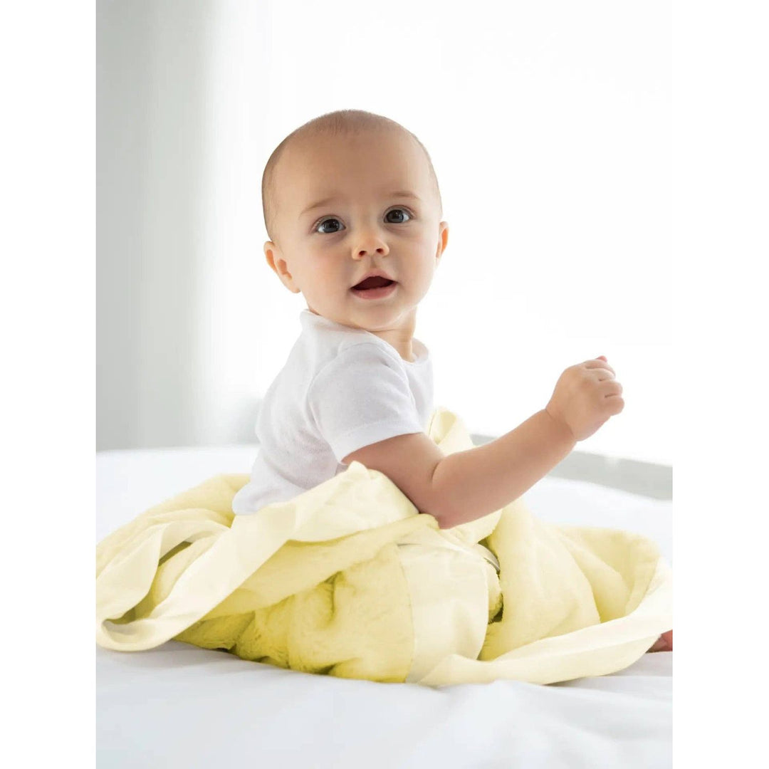 Baby sitting on a white surface with a yellow blanket