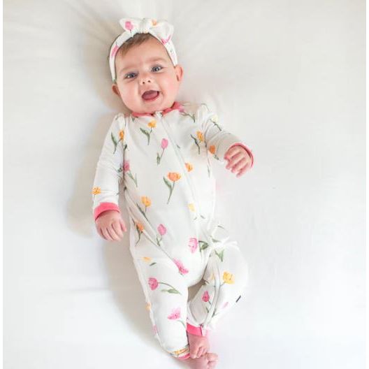 Baby wearing a floral onesie and headband on a white background