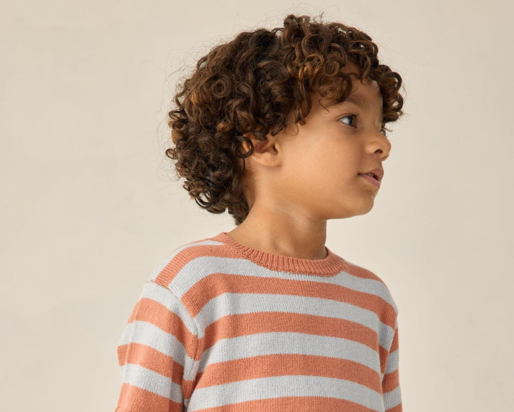 Child wearing a striped sweater against a plain background