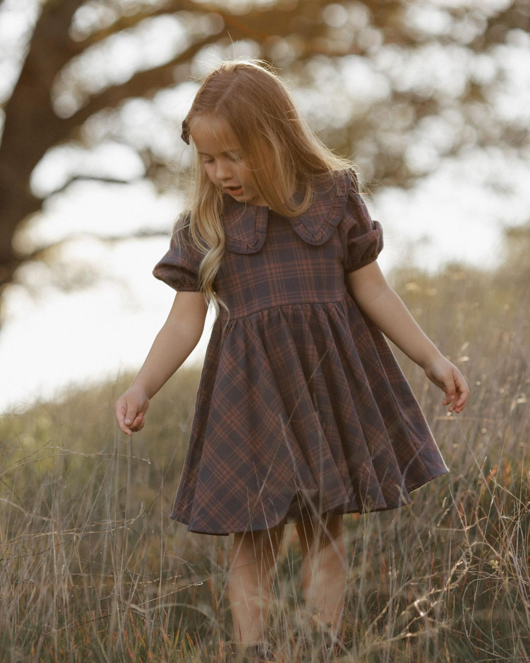 Girl in a Rylee + Cru dress walking and imagining in a field