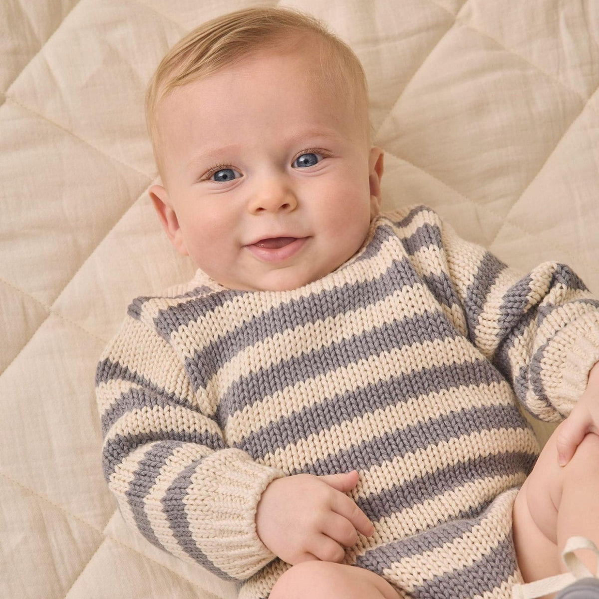 Baby in a blue and white striped sweater smiling